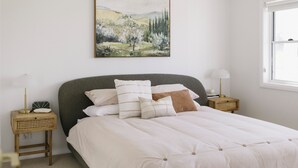 A bedroom with a bed, a nightstand, a lamp, and a painting on the wall.