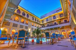 Ein Hotelinnenhof mit Pool, Sitzgelegenheiten und aufwendiger Architektur.