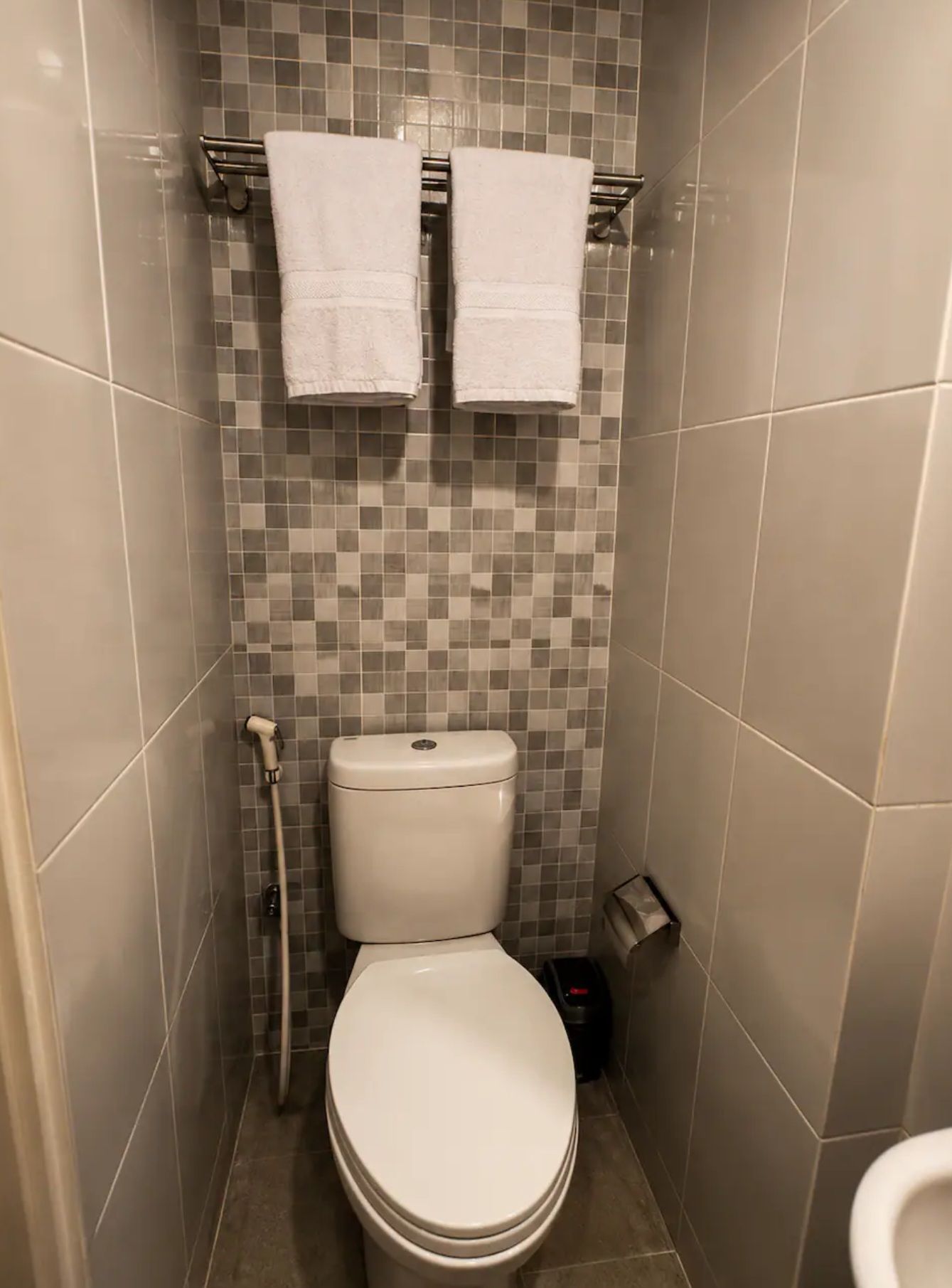 Kylpyhuoneessa on wc, suihku ja kaksi pyyhettä, jotka on ripustettu pyyhetelineeseen.