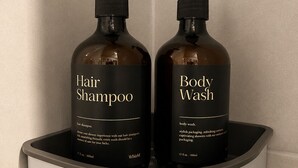 Duas embalagens de champô e gel de banho Whizlh numa prateleira de casa de banho.