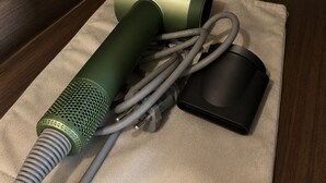A power strip with a green device and a black device on a beige cloth. - Casa Velo Residence (Teluknaga)
