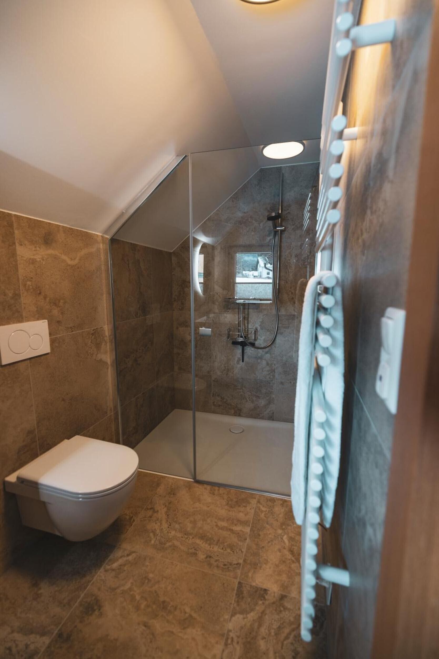 Ein modernes Badezimmer mit einer gläsernen Duschkabine, einer Toilette und einem Handtuchhalter.