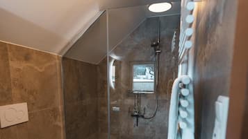 Ein modernes Badezimmer mit einer gläsernen Duschkabine, einer Toilette und einem Handtuchhalter.