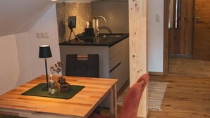 Une cuisine de taille réduite avec une table en bois, une chaise rouge et un luminaire suspendu.