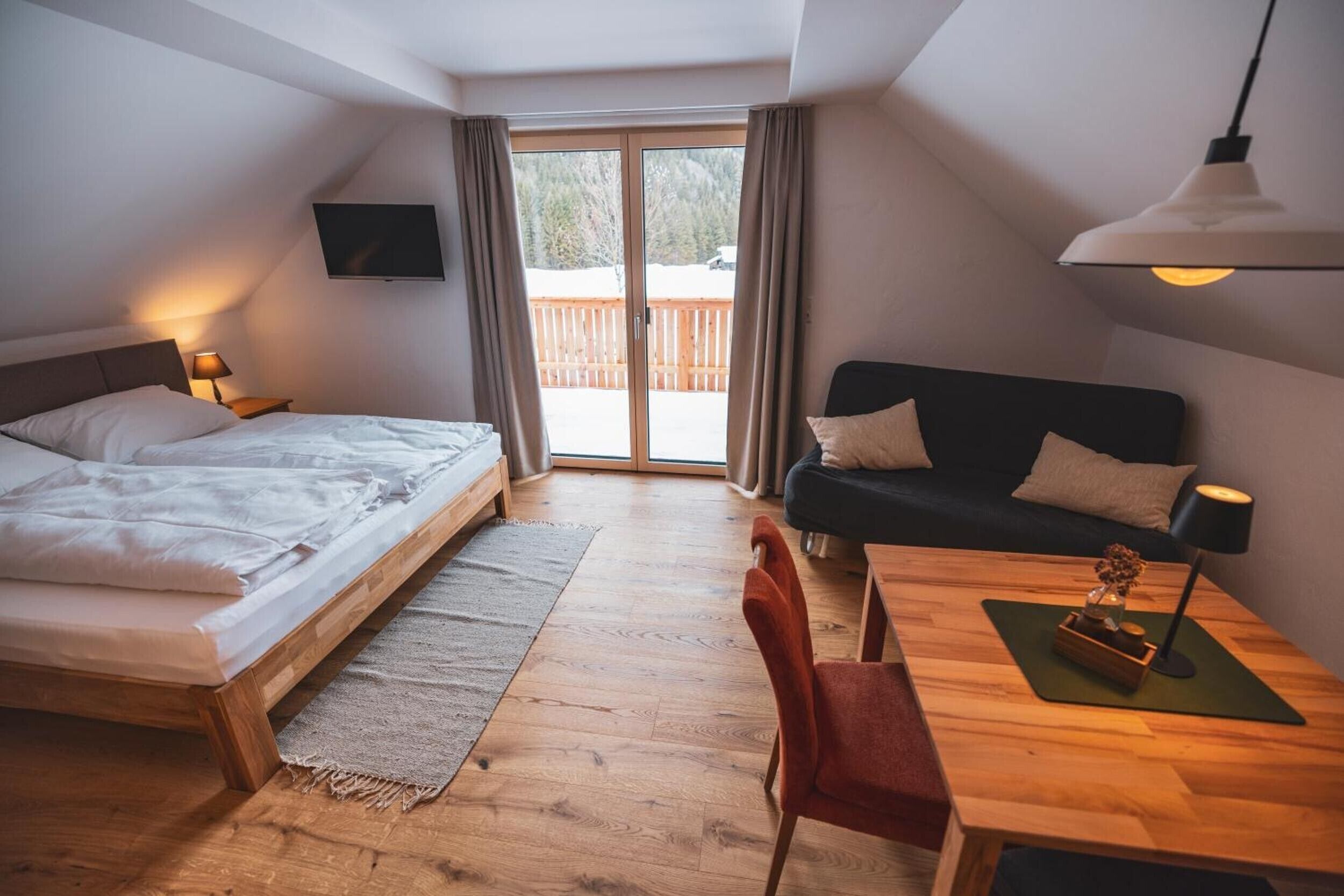 Un dormitorio con cama, sofá, mesa y televisor.