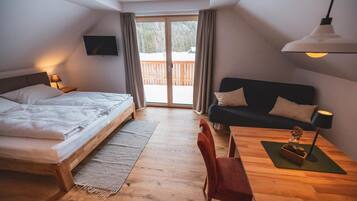 Un dormitorio con cama, sofá, mesa y televisor.