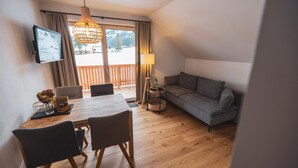 En moderne stue med et træspisebord, en grå sofa og et fjernsyn monteret på væggen.