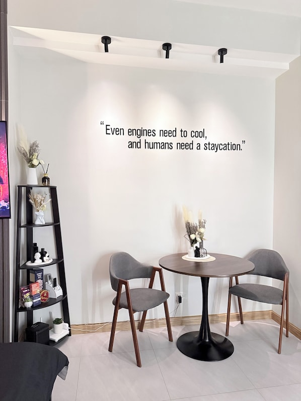 A modern room with a round table, two chairs, a bookshelf, and a decorative quote on the wall.