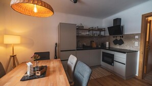 Eine kompakte Küche mit Essbereich, einem Kühlschrank und einem über der Arbeitsfläche angebrachten Fernseher.