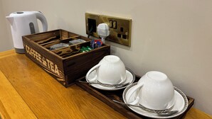 En træ-kaffestation med elkedel, kaffemaskine og bakke med to kopper og underkopper.
