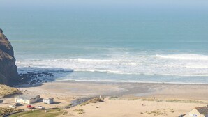 Vista costera con playa, un acantilado y algunos edificios.