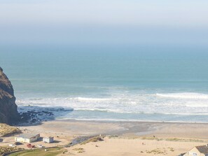 Eine Küstenansicht mit Strand, einer Klippe und einigen Gebäuden.