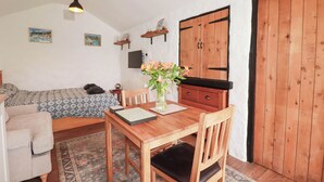 Una habitación acogedora con cama, una mesa de comedor con sillas, un armario de madera y una puerta grande de madera.
