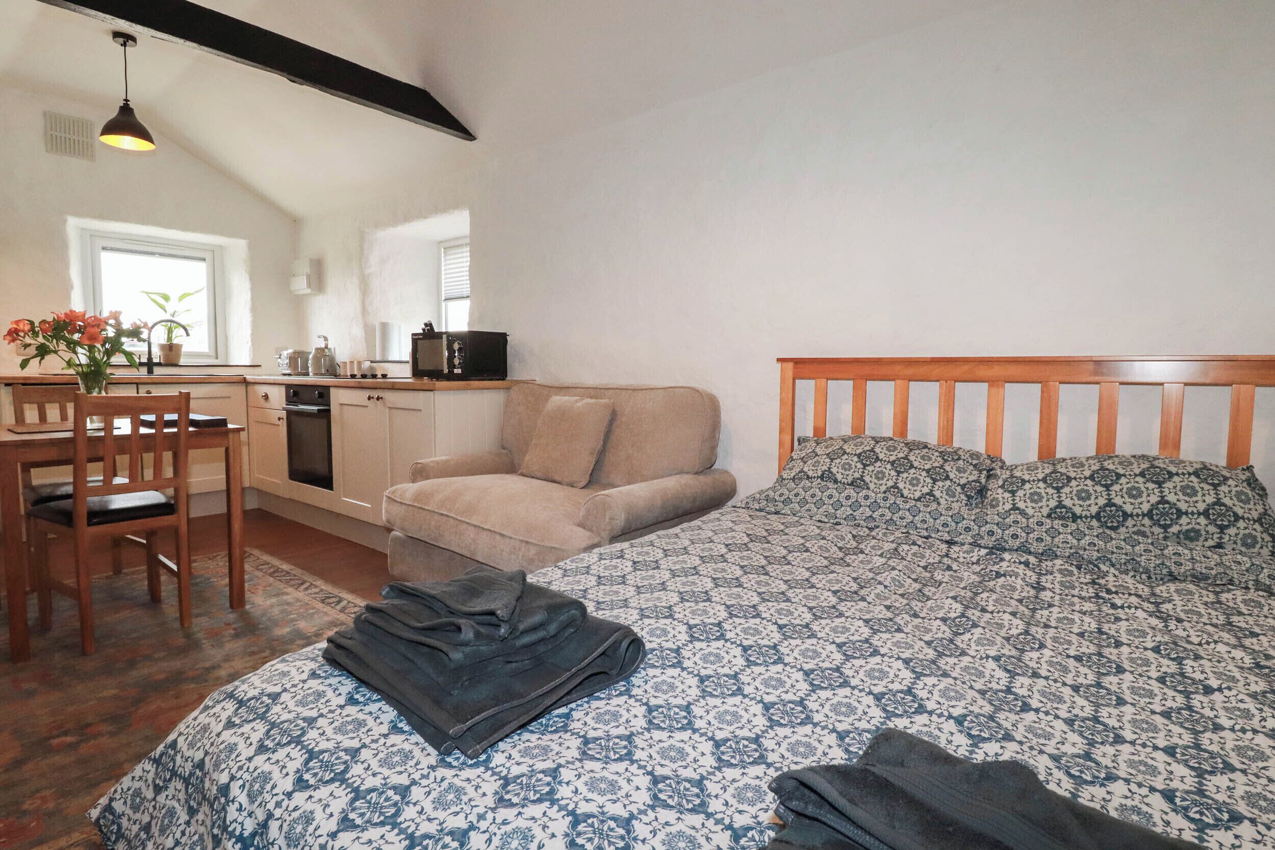 Una habitación compacta con cama, sofá, una kitchenette pequeña y zona de comedor.