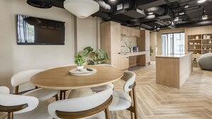A modern kitchen with wooden cabinets, a round dining table, and chairs. - Student Only The Sailworks (Lancaster)