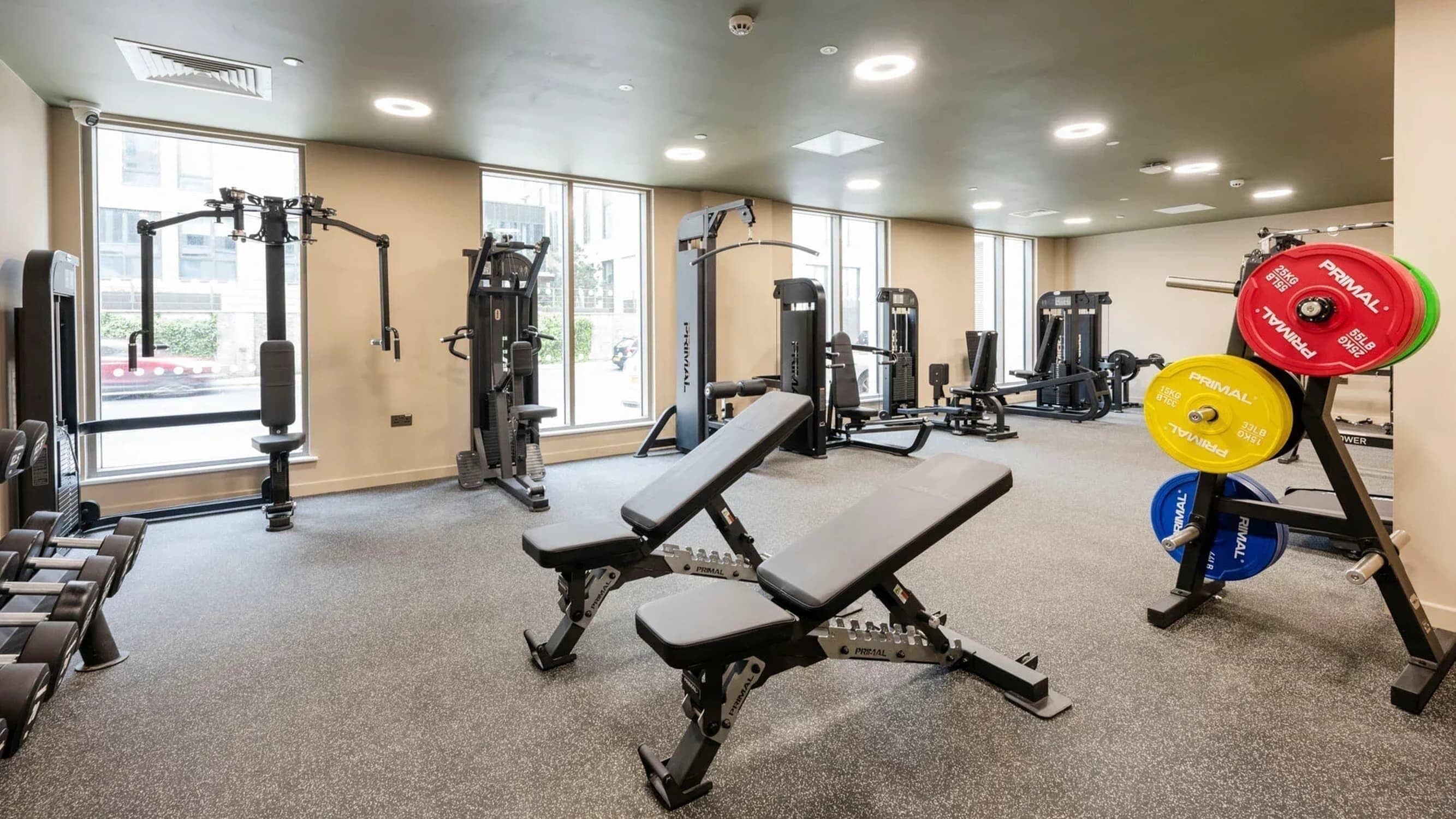 A gym with various exercise equipment, including benches, weight machines, and free weights.