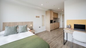 A hotel room with a bed, a desk with a laptop, a kitchenette, and a bathroom. - Student Only The Sailworks (Lancaster)
