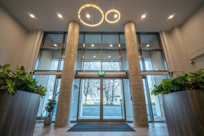 A modern entrance with glass doors, two large columns, and a ceiling with circular light fixtures. - Student Only The Sailworks (Lancaster)