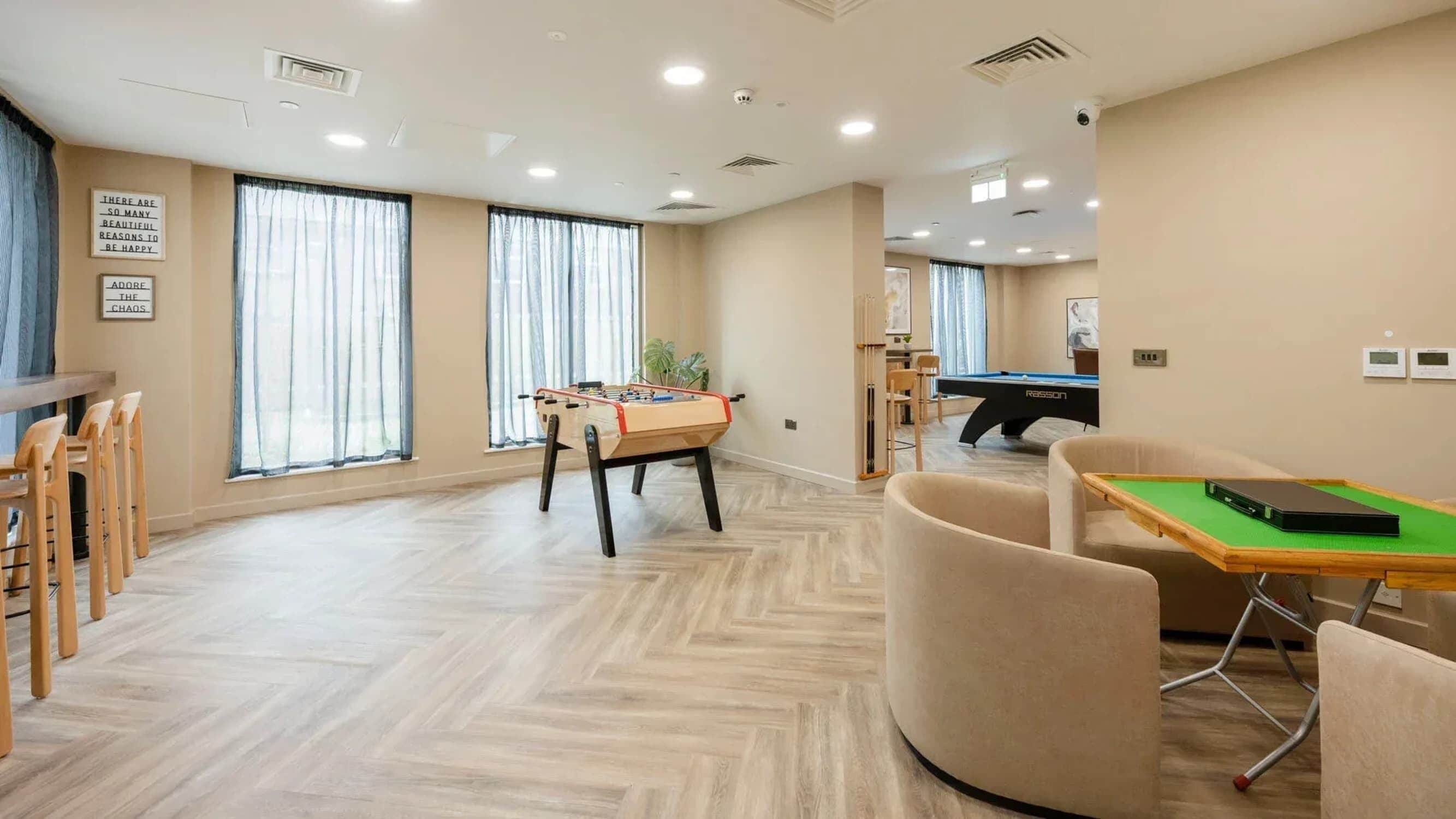 A spacious room with a pool table, a foosball table, and a dining area with chairs.