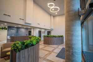 A spacious lobby with modern furnishings, a reception desk, and a large planter with greenery. - Student Only The Sailworks (Lancaster)