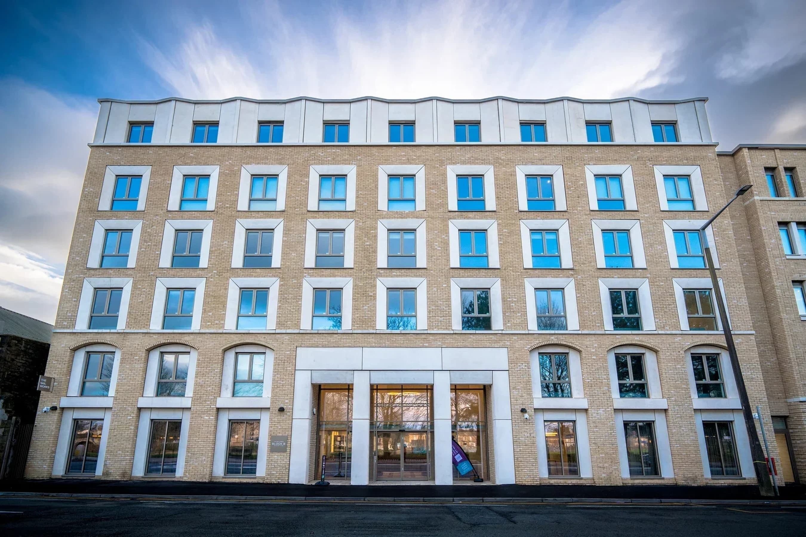 Un hôtel à plusieurs étages, doté d’une façade symétrique, de grandes fenêtres et d’une entrée centrale.