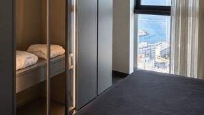 Ein Hotelzimmer mit einem Bett, einem Schrank mit Spiegel und einem Fenster mit Blick auf die Stadt.