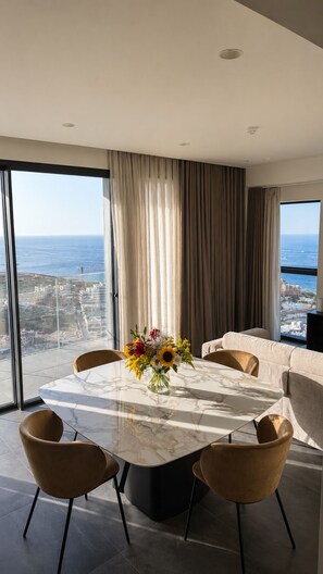 A modern dining area with a marble table, four chairs, and a vase of flowers. - Luxury 26th Floor Apartment with Panoramic Sea Views Mercury Towers St Julian (St. Julian's)