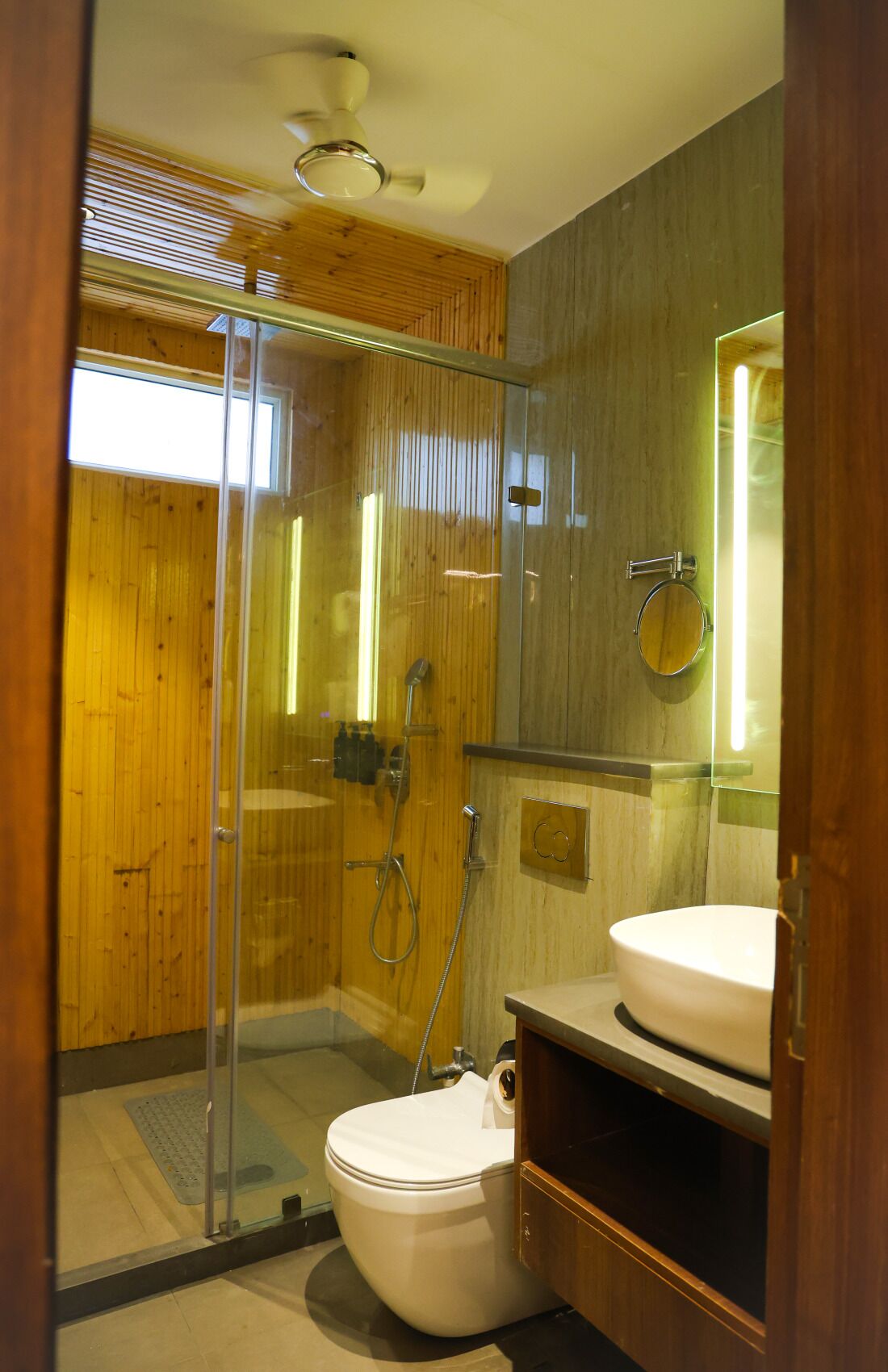 Ein modernes Badezimmer mit einer gläsernen Duschkabine, einer Toilette und einem Waschtisch mit Spiegel.