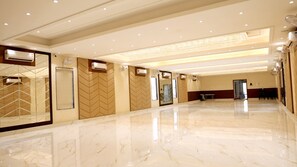 Un amplio vestíbulo de hotel con piso de mármol, varias unidades de aire acondicionado y un espejo grande.