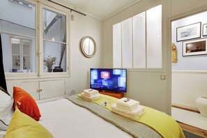 Ein Hotelzimmer mit Bett, Fernseher, Fenster und Spiegel.