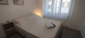 Ein Schlafzimmer mit einem Bett, einem Nachttisch und einem Fenster mit Vorhängen.
