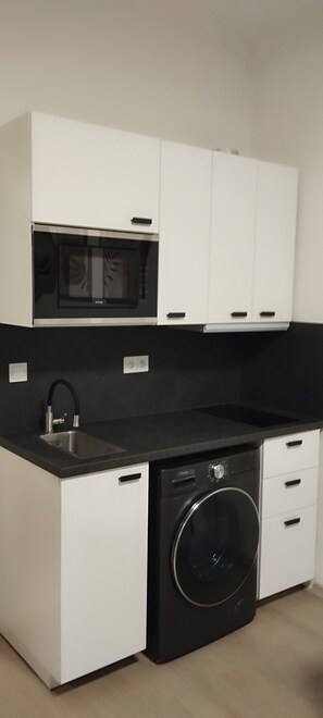 Eine kompakte Küche mit eingebautem Backofen, Mikrowelle und Geschirrspüler.