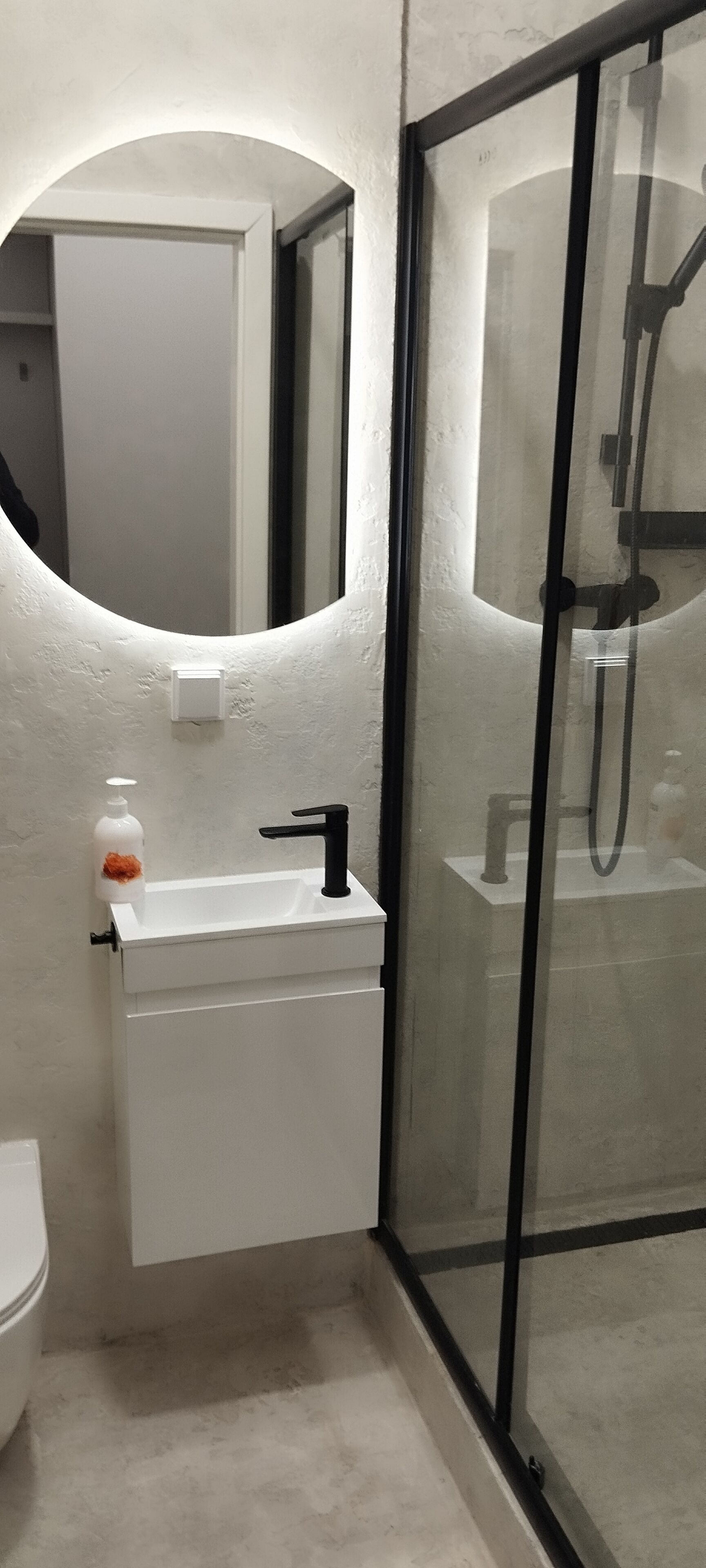 A bathroom with a white sink, a mirror, and a glass shower enclosure.