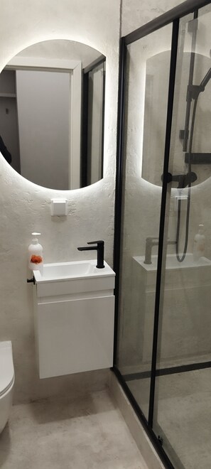 A bathroom with a white sink, a mirror, and a glass shower enclosure.