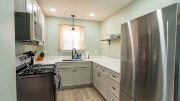 A compact kitchen with a stainless steel refrigerator, a built-in oven, and a microwave.