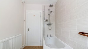 Un baño con una bañera blanca, una ducha y una puerta blanca.