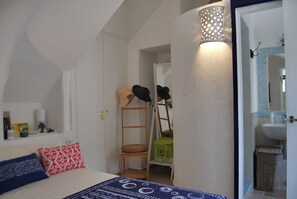 Ein Schlafzimmer mit einem Bett, Kissen, einer Leiter und einem an der Wand befestigten Regal mit Hüten.
