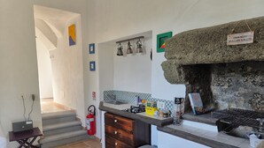 Een keuken met een stenen oven, een koffieapparaat en een klein spoelgedeelte.
