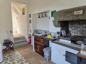 Eine Küche mit Steinofen, Kaffeemaschine und kleinem Spülbecken.