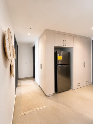 Une cuisine moderne avec un réfrigérateur en acier inoxydable, des meubles de couleur claire et un tapis à motifs.