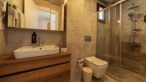 A modern bathroom with a large sink, toilet, and glass-enclosed shower. - Kiraz Vela Selimiye (Marmaris)