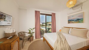 A hotel room with a bed, a desk with a computer, a chair, a plant, and a painting on the wall. - Kiraz Vela Selimiye (Marmaris)