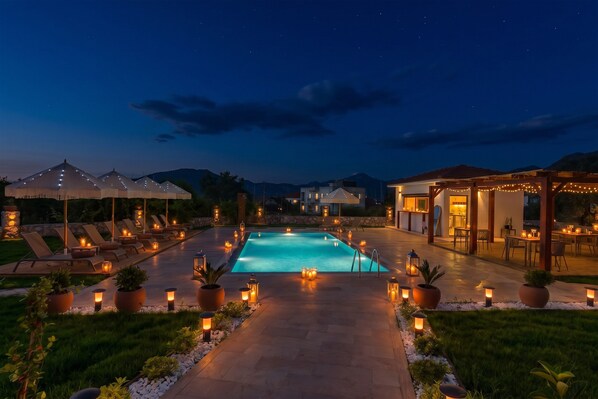 A nighttime outdoor pool area with lounge chairs, a swimming pool, and ambient lighting. - Kiraz Vela Selimiye (Marmaris)