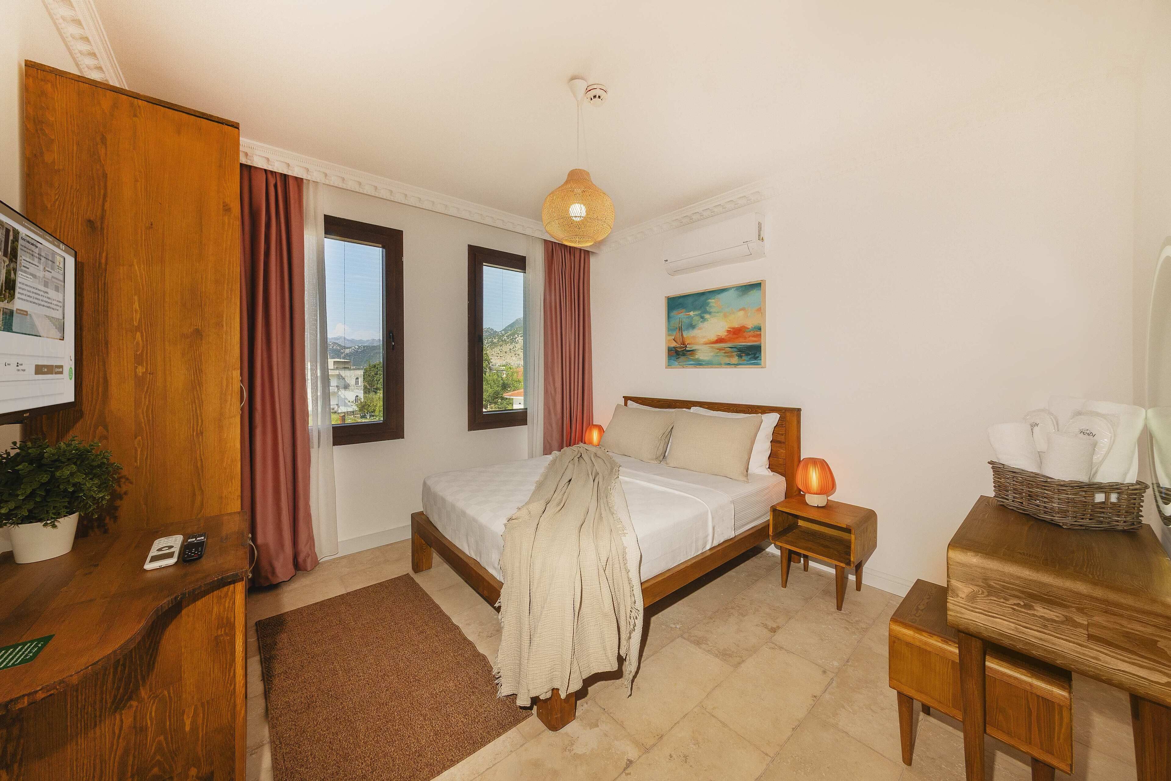 A bedroom with a bed, bedside tables, a desk, a plant, a painting, and a view through the window.