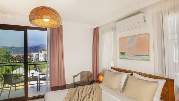 A hotel room with a bed, a chair, a balcony, and a painting on the wall. - Kiraz Vela Selimiye (Marmaris)