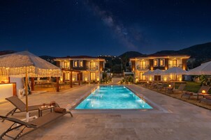 Un hotel con piscina, asientos exteriores y vista al cielo nocturno.