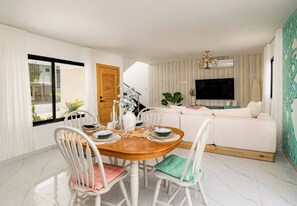 A modern living room with a dining area, a sofa, a TV, and a staircase leading to another level. - Villa for 6 People in Punta Cana (Punta Cana)