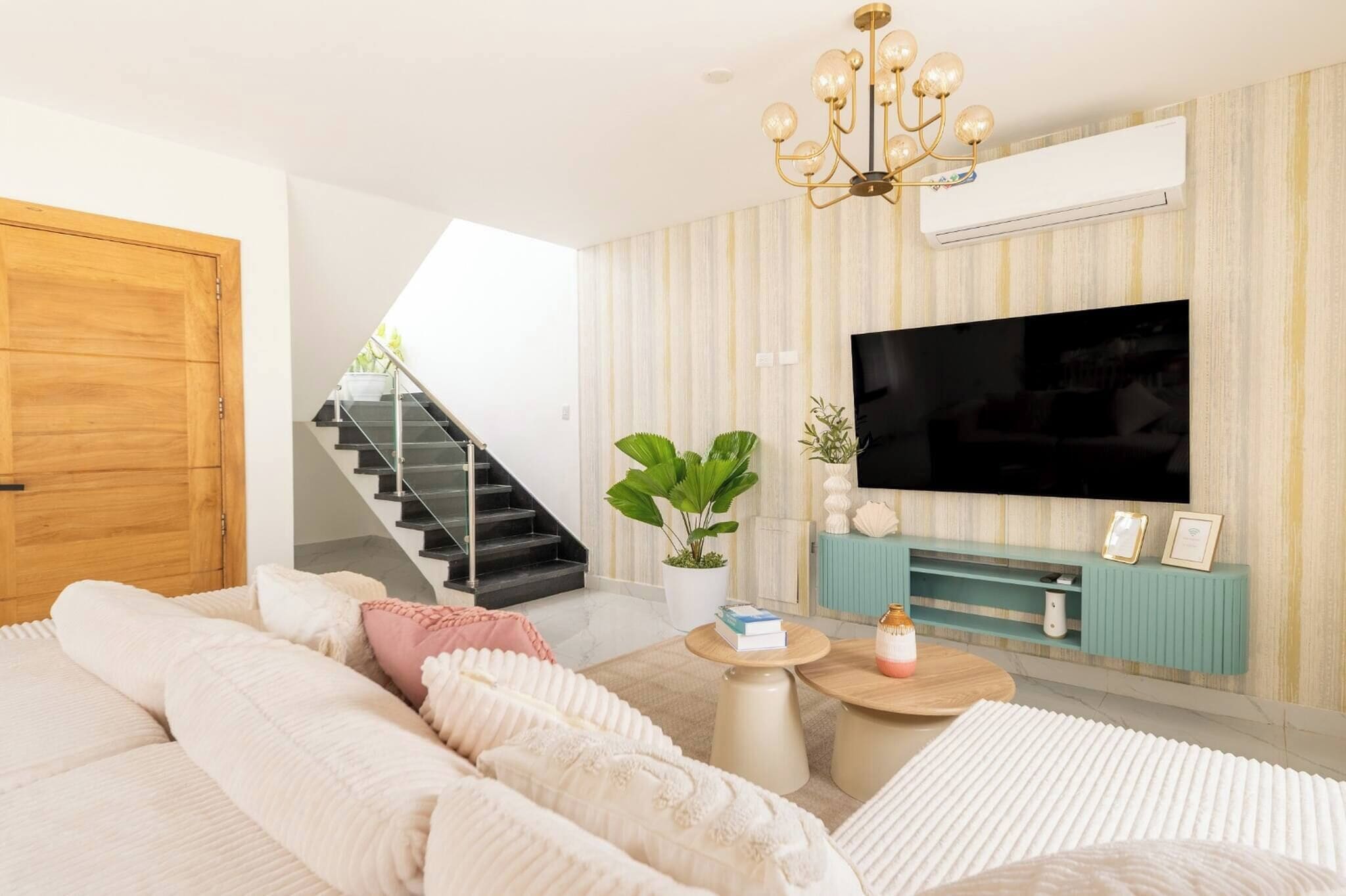 Een moderne woonkamer met een bank, salontafel, televisie en een trap.