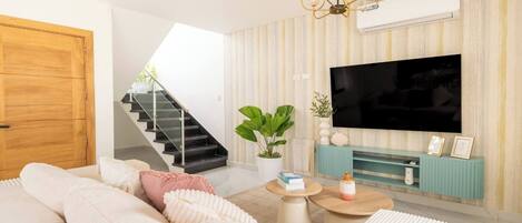 Una sala de estar moderna con sofá, mesa de centro, televisor y una escalera.