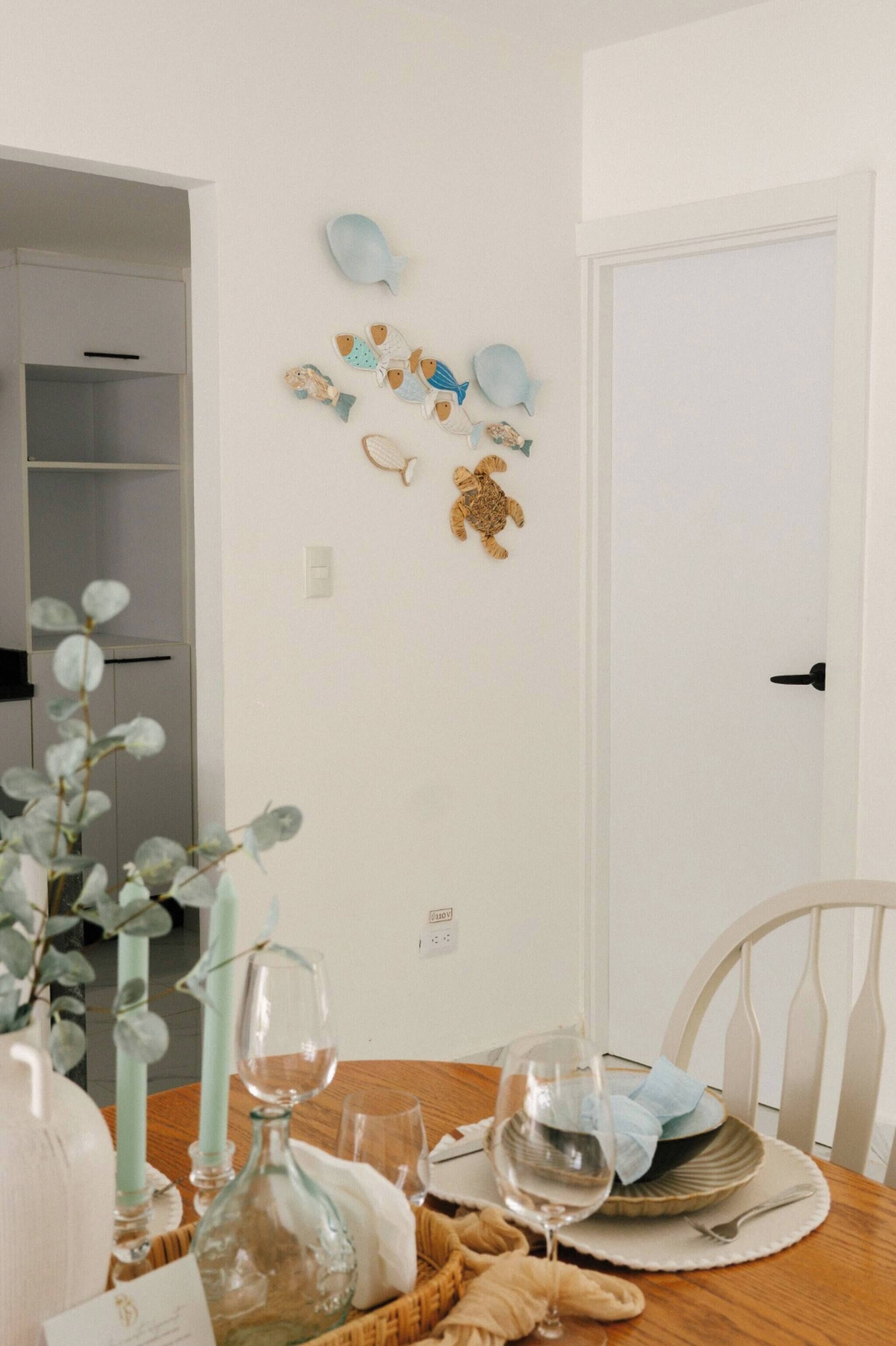 A dining area with a wooden table, wine glasses, and a vase with a plant.